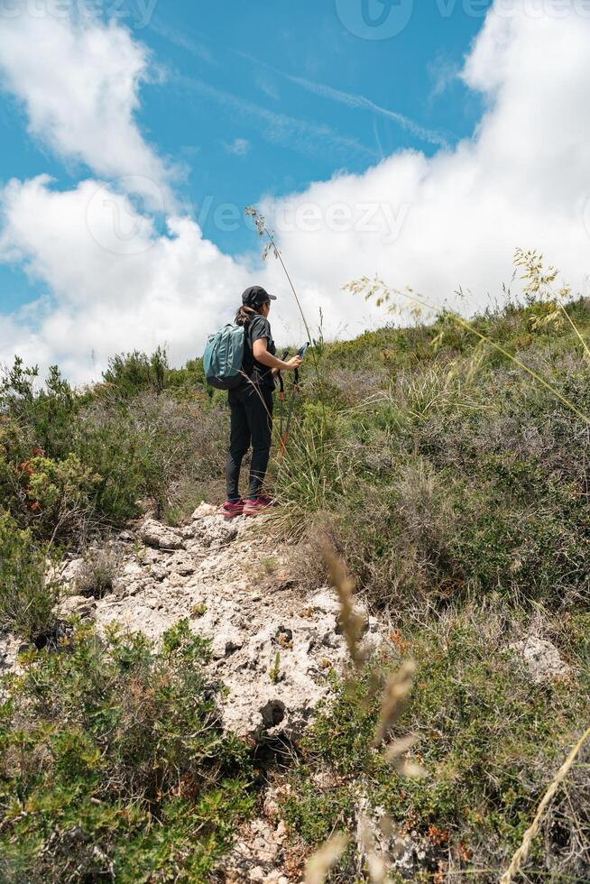Woman takes a break while climbing the mountain, while taking a breath to continue her path. photo