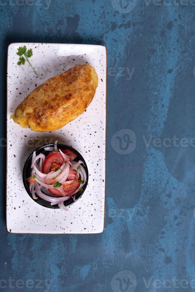 Tasty Peruvian delicacy, golden stuffed potato with a salad seen from above. photo