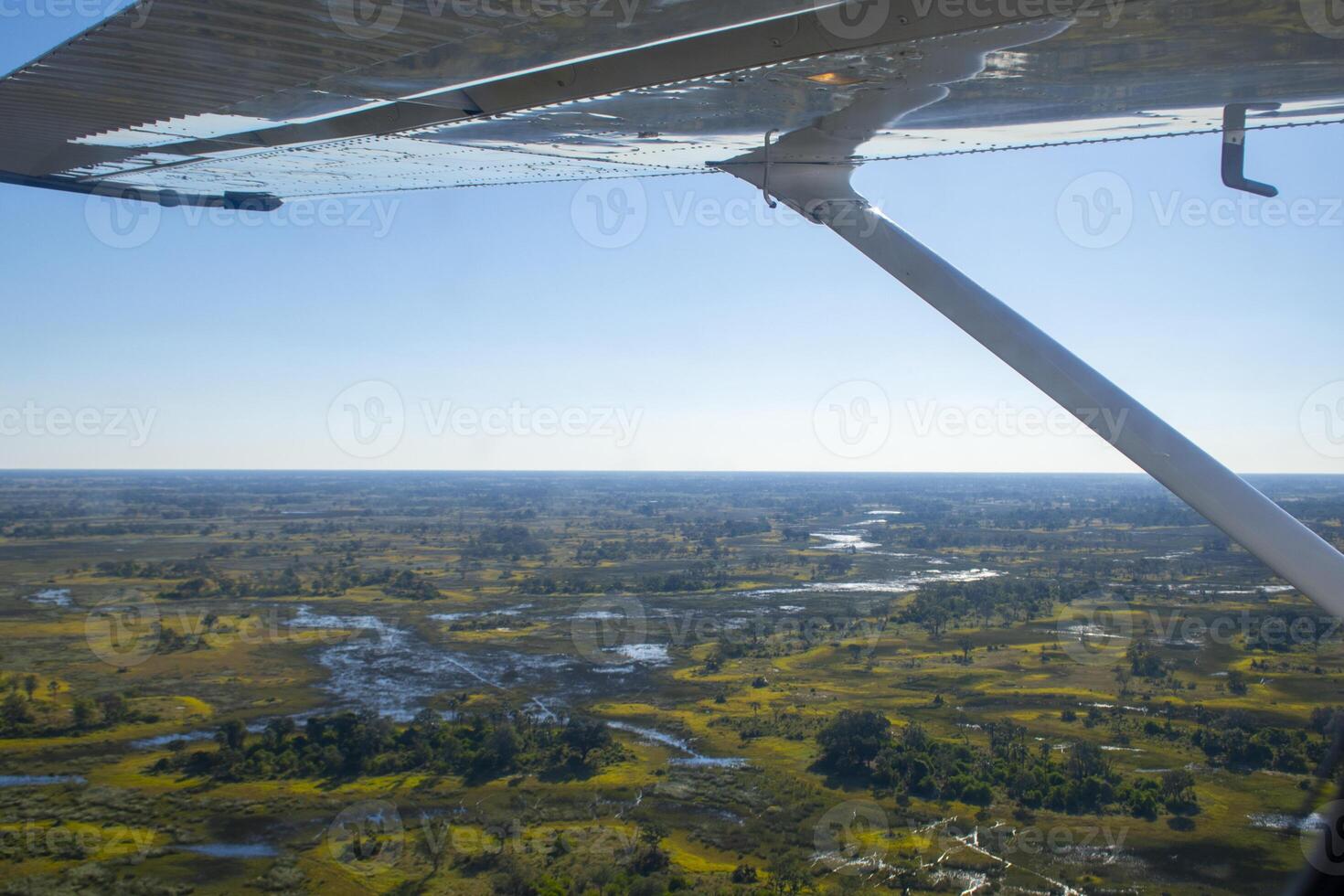 Aerial view at Moremi national park in Botswana, Africa, as seen from a small aircraft. Wing visible, bright sunshine on blue sky. photo