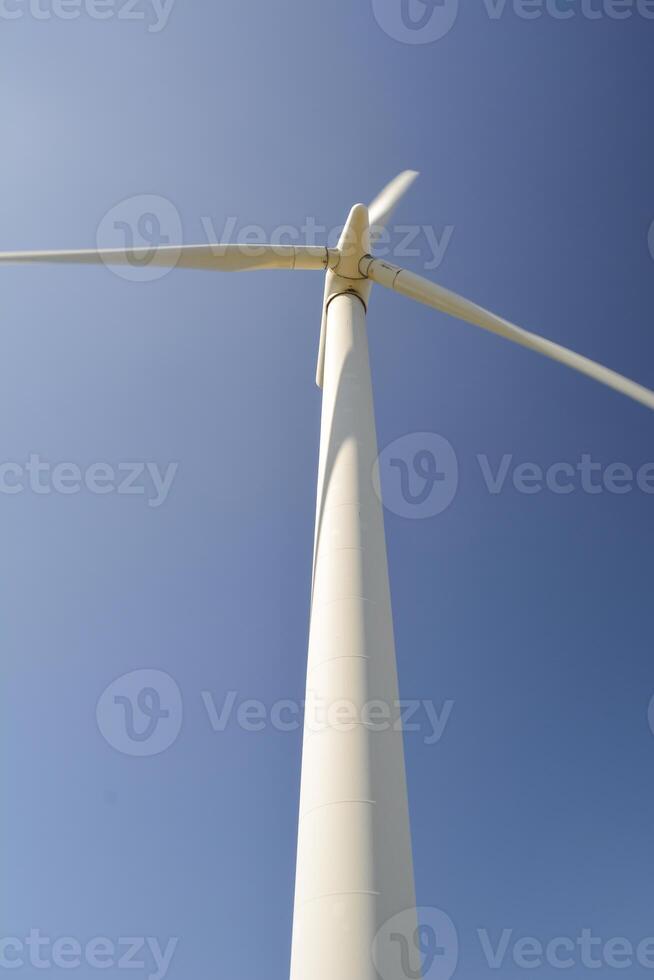 Close-up and low angle view of spinning blades of a wind turbine generating renewable energy photo