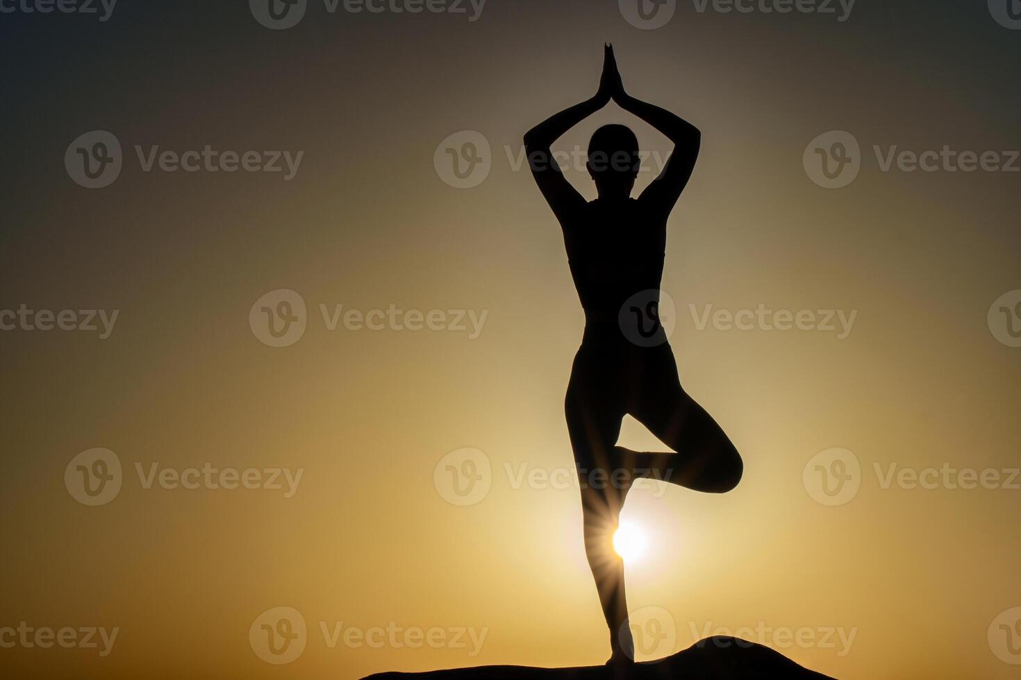 Sunset colors surround the silhouette of a girl standing on one leg with outstretched arms above her head, creating an atmosphere of calm and inner peace photo