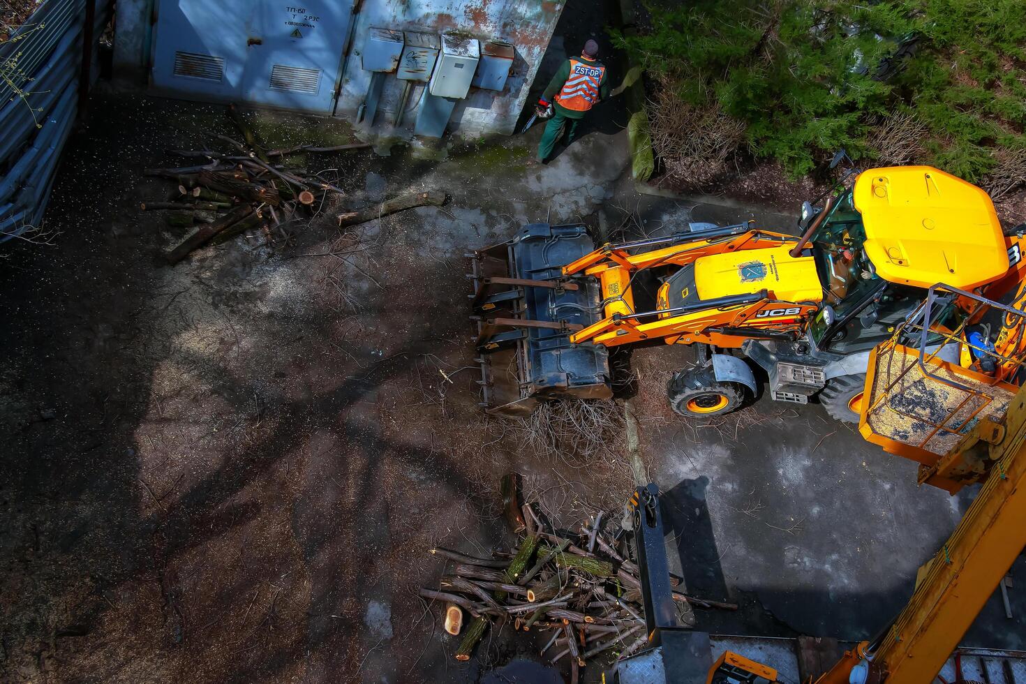 Dnepr, Ukraine - 03.20.2024 A bulldozer collects branches after pruning trees. View from above photo