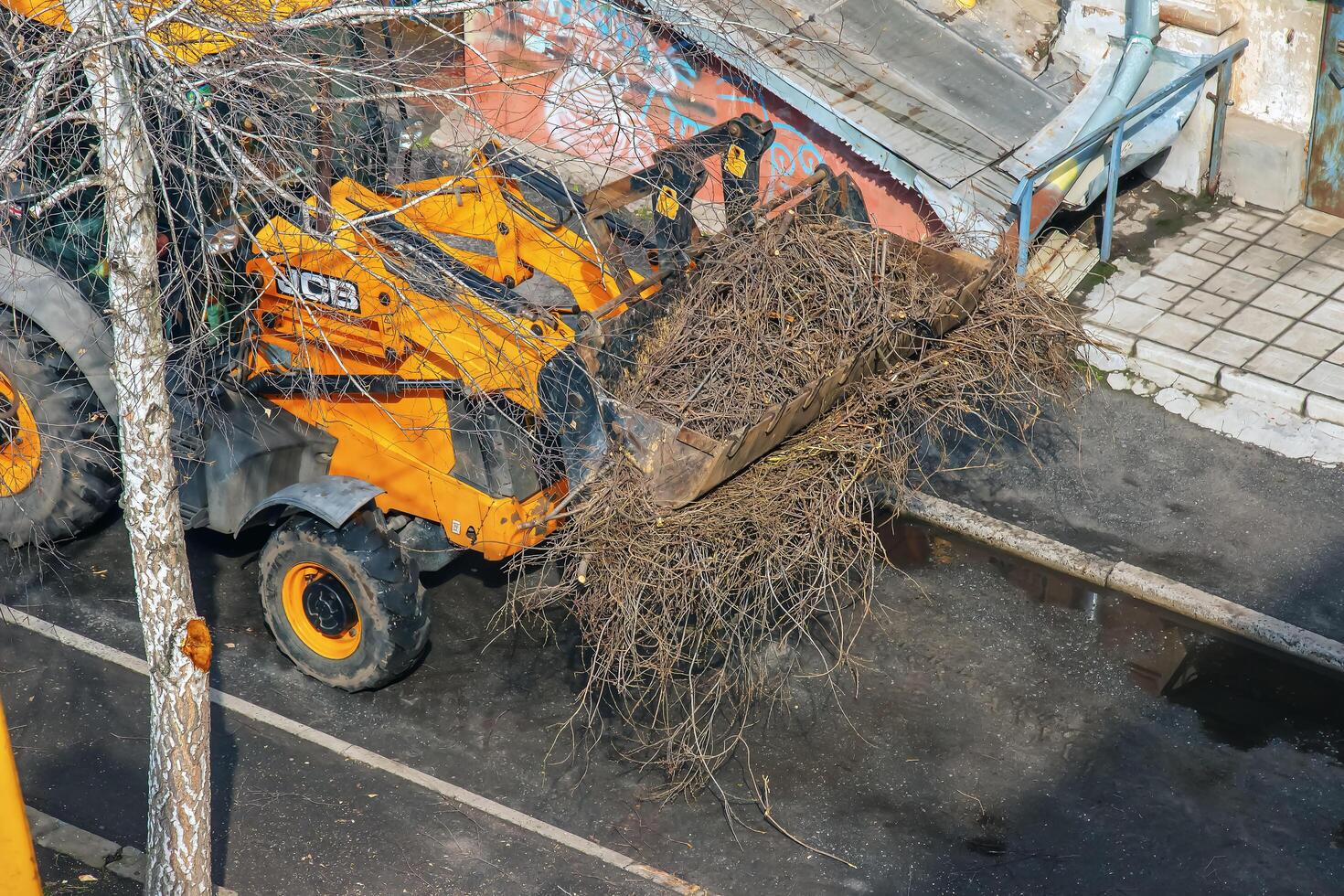 Dnepr, Ukraine - 03.20.2024 A bulldozer collects branches after pruning trees. View from above photo