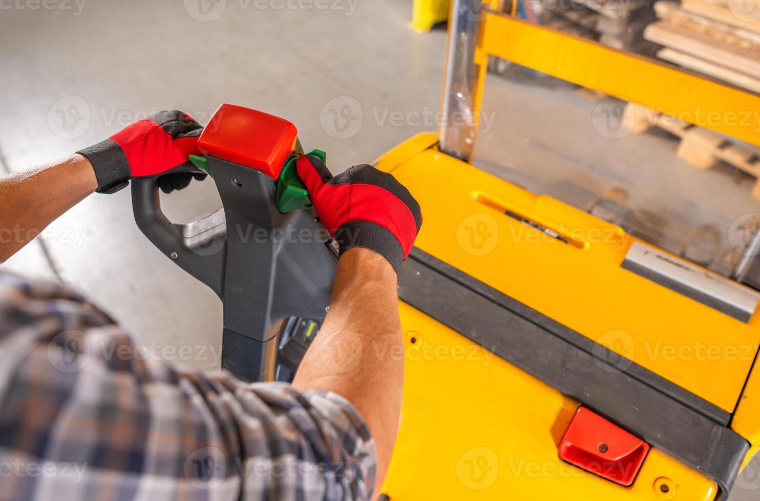 Worker Pushing Yellow Forklift in Warehouse photo