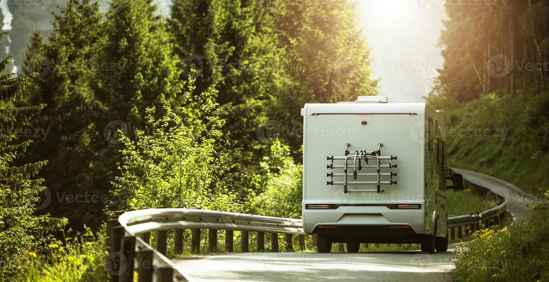 Modern RV Camper Van Driving Along Forested Road photo