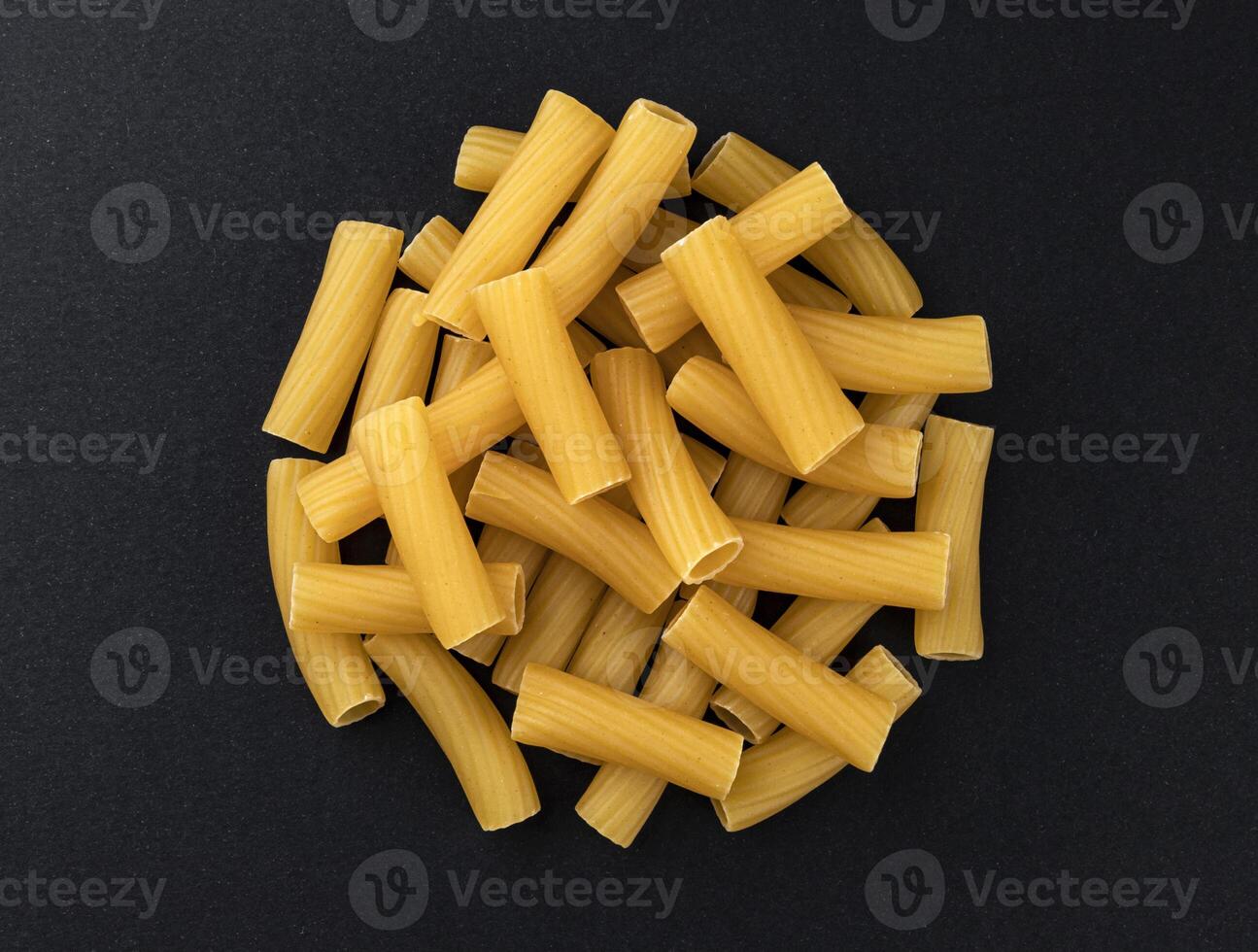 Raw spiral tortiglioni pasta isolated on black background, top view photo