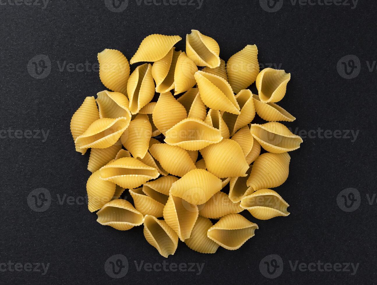 Conchiglie rigate. Raw striped shell pasta on black background, top view photo