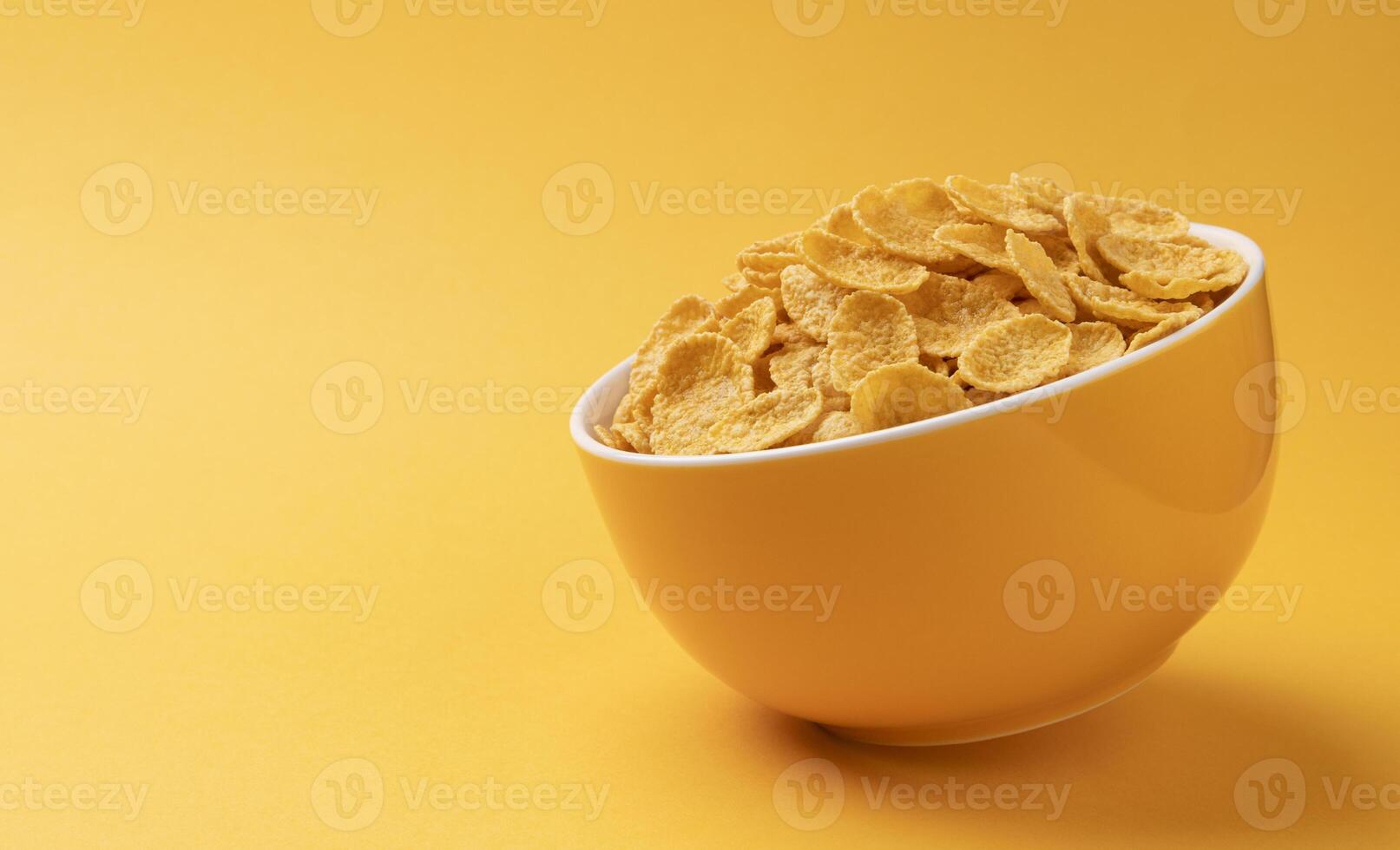 Ceramic bowl of corn flakes on yellow background photo
