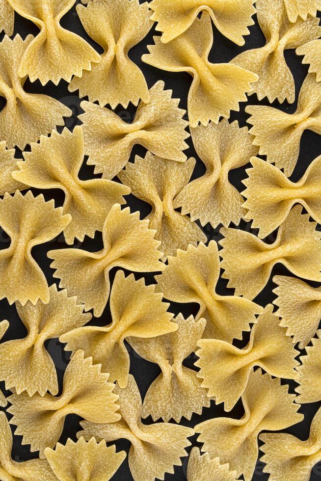 Farfalle pasta pattern on black background, top view, flat lay texture photo
