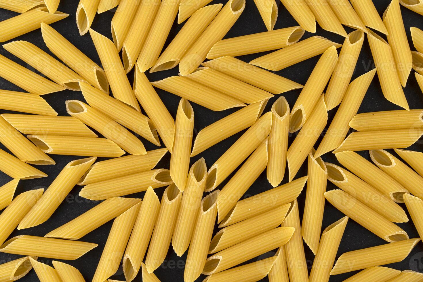 Penne rigate pasta pattern on black background, top view, flat lay texture photo
