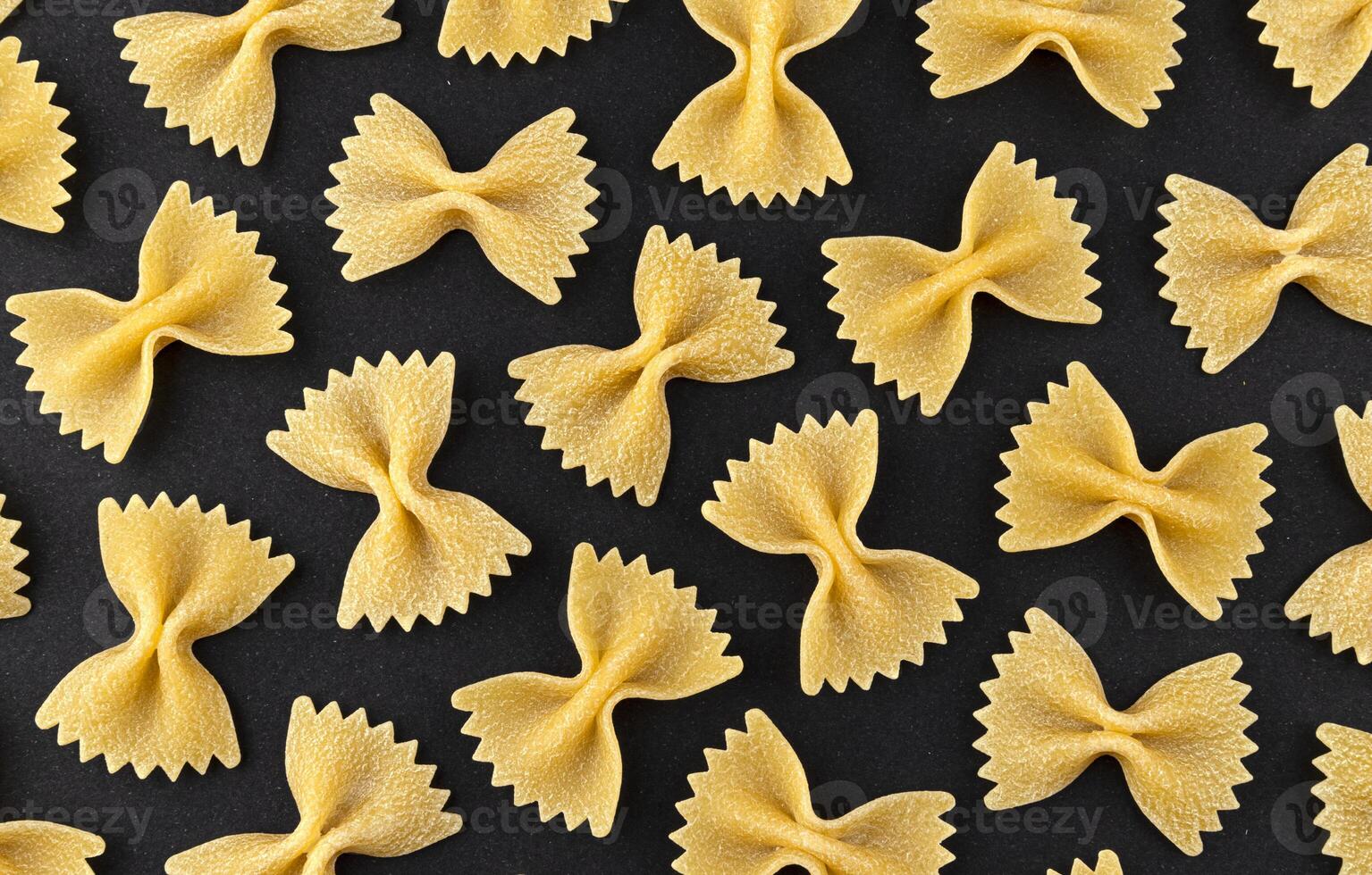 Farfalle pasta pattern on black background, top view, flat lay texture photo