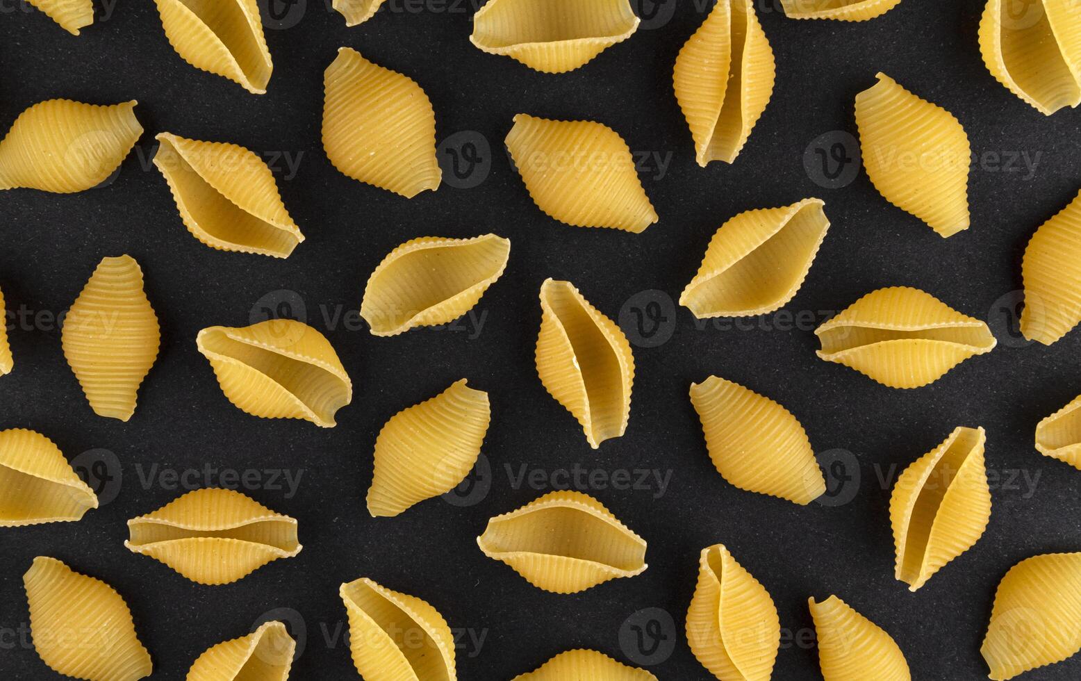 Dry shell pasta pattern on black background, top view photo