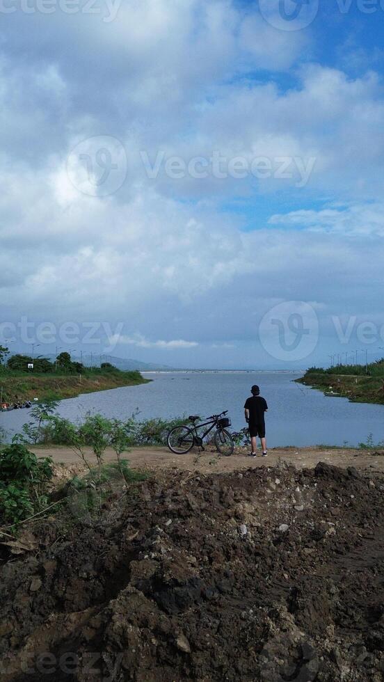 Man Resting with His Bicycle by the Lake, Enjoying the Beautiful Summer Morning Background photo