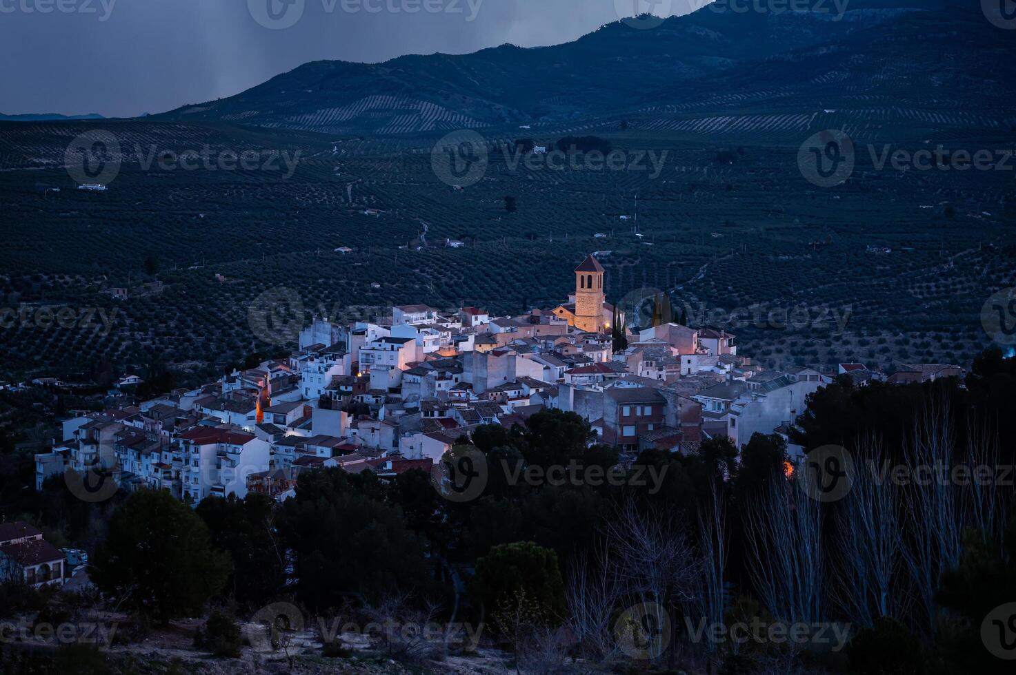 View from the hill of medieval historical urban village of Quesada in the province of Jaen, at dawn with the illuminated bell tower and while houses. Beauty in Spain nature. Travel and tourism concept photo