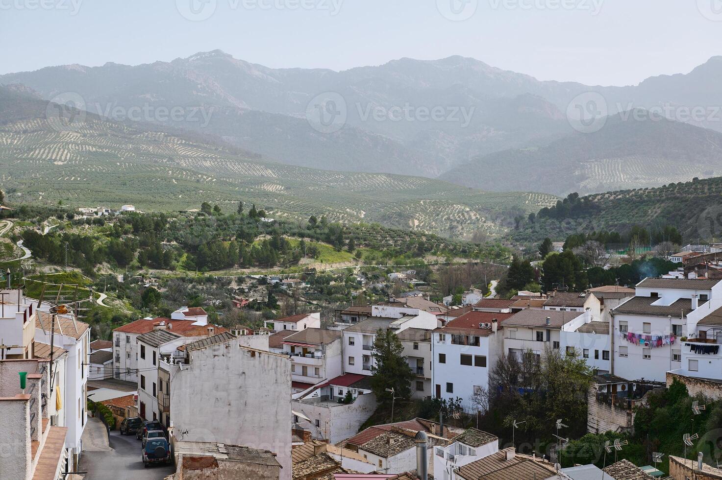 View of beautiful medieval district of Spanish village, Quesada in the region of Jaen, Andalusia Spain in mountains. White houses with red tiles over mountain ridge background of La Sierra de Cazorla photo