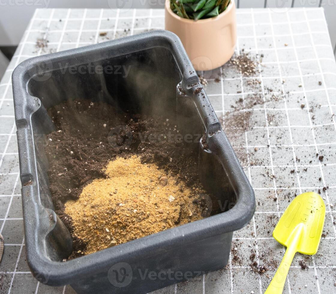 Ingredients for the soil of home potted plants, peat, earth, sand, perlite, vermiculite, coconut. A mixture for planting plants in a pot florist's gloved hands are mixing in a container photo