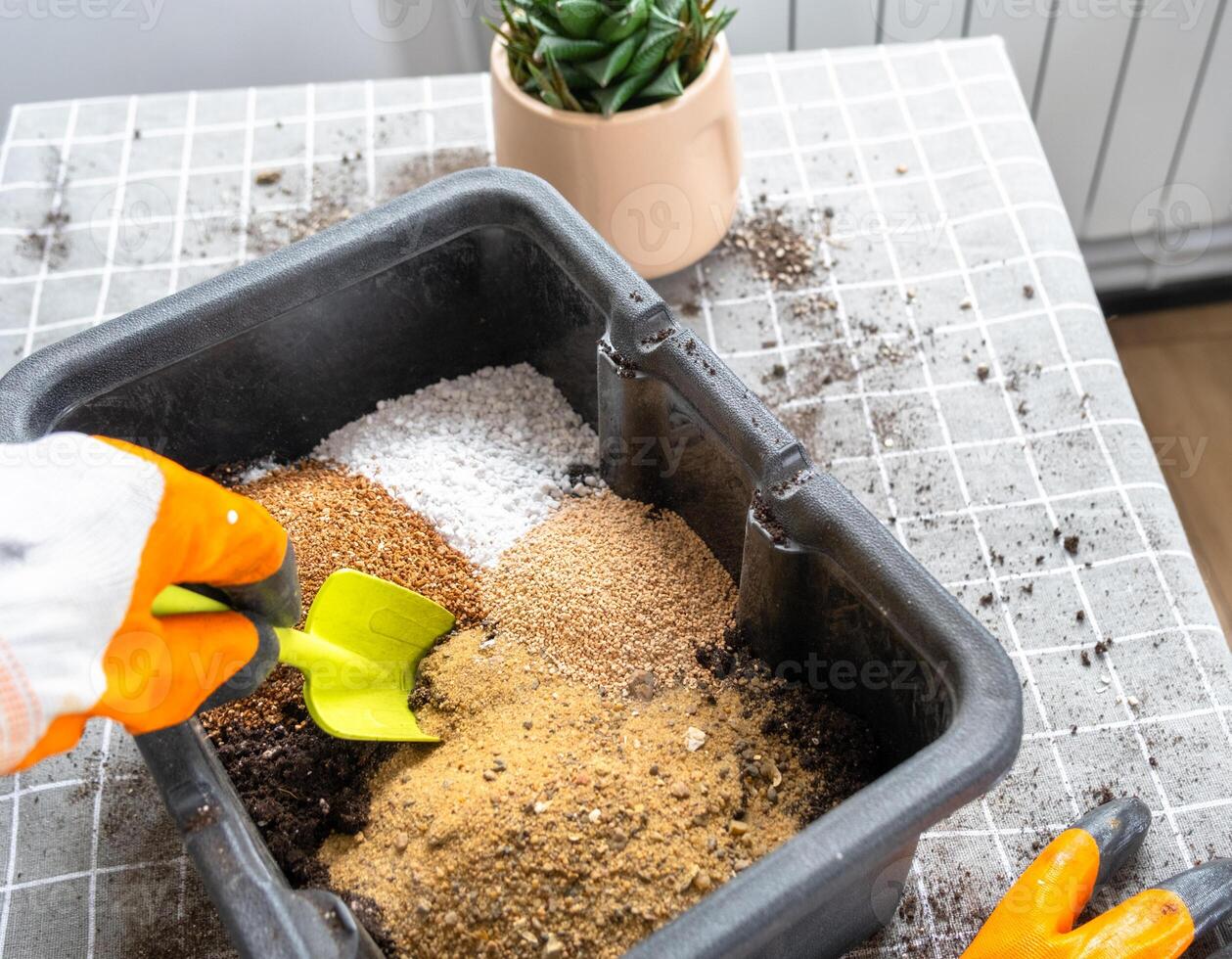 Ingredients for the soil of home potted plants, peat, earth, sand, perlite, vermiculite, coconut. A mixture for planting plants in a pot florist's gloved hands are mixing in a container photo