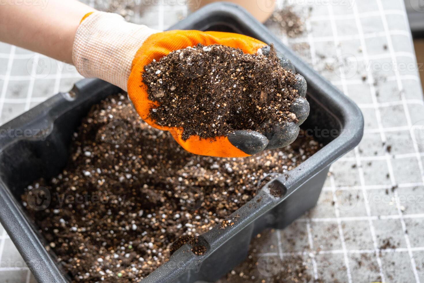 Ingredients for the soil of home potted plants, peat, earth, sand, perlite, vermiculite, coconut. A mixture for planting plants in a pot florist's gloved hands are mixing in a container photo