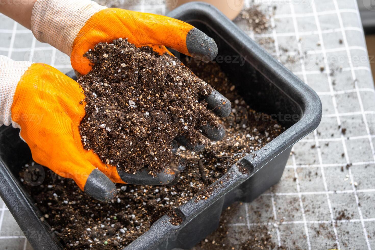 Ingredients for the soil of home potted plants, peat, earth, sand, perlite, vermiculite, coconut. A mixture for planting plants in a pot florist's gloved hands are mixing in a container photo