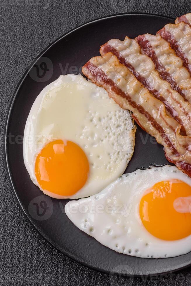 English breakfast with fried eggs, bacon, beans, tomatoes, spices and herbs photo