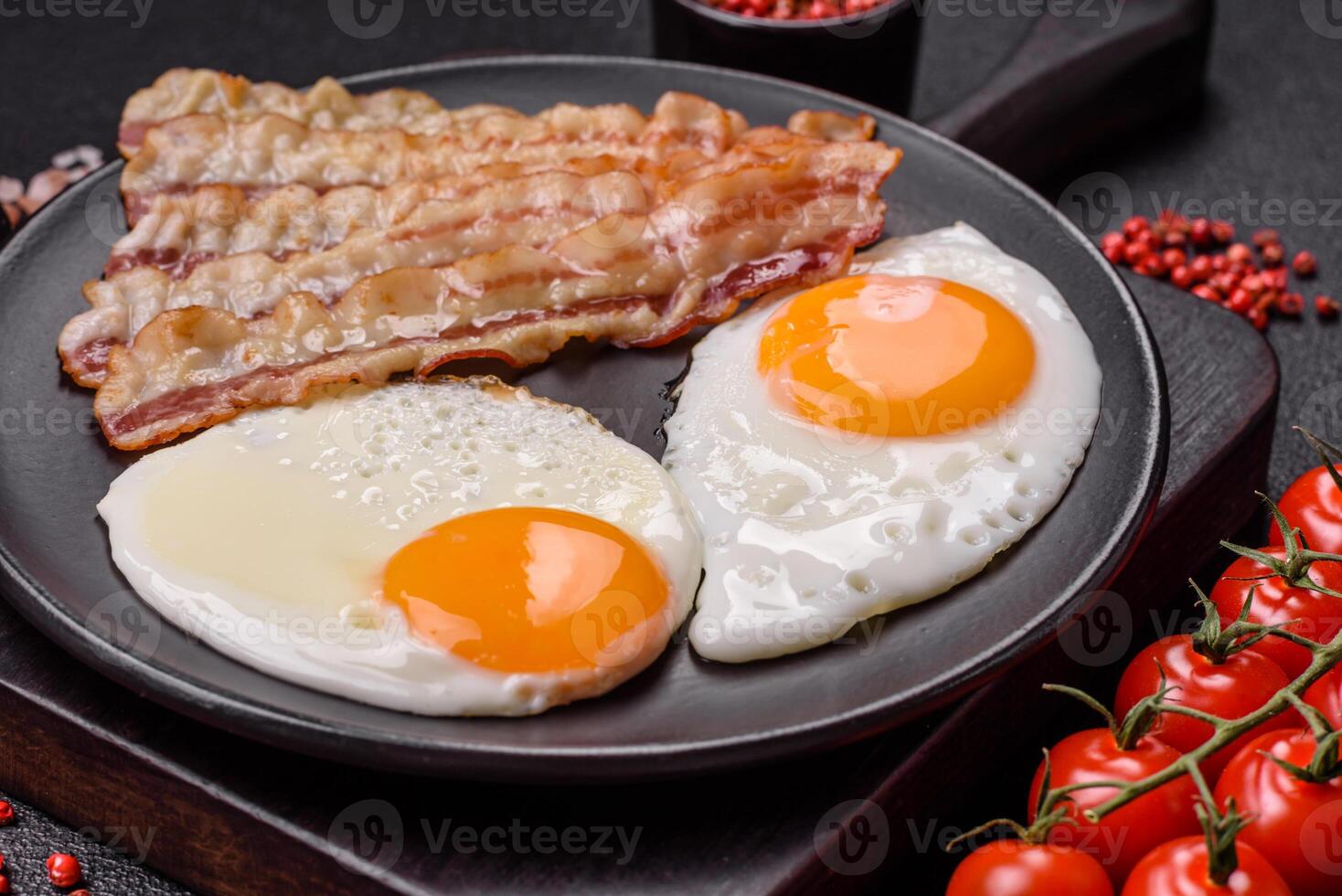 English breakfast with fried eggs, bacon, beans, tomatoes, spices and herbs photo