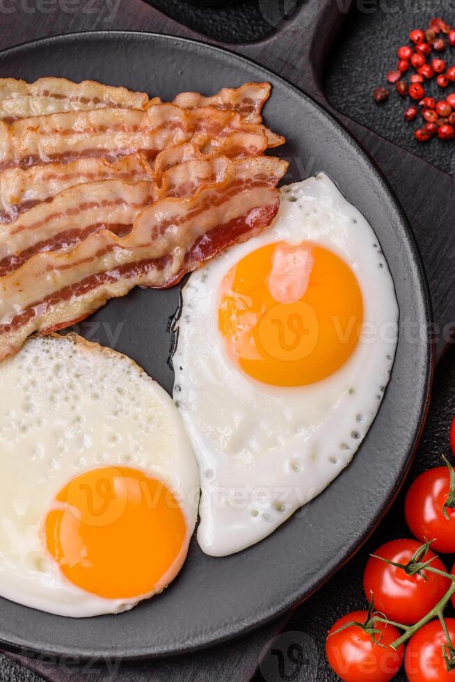English breakfast with fried eggs, bacon, beans, tomatoes, spices and herbs photo