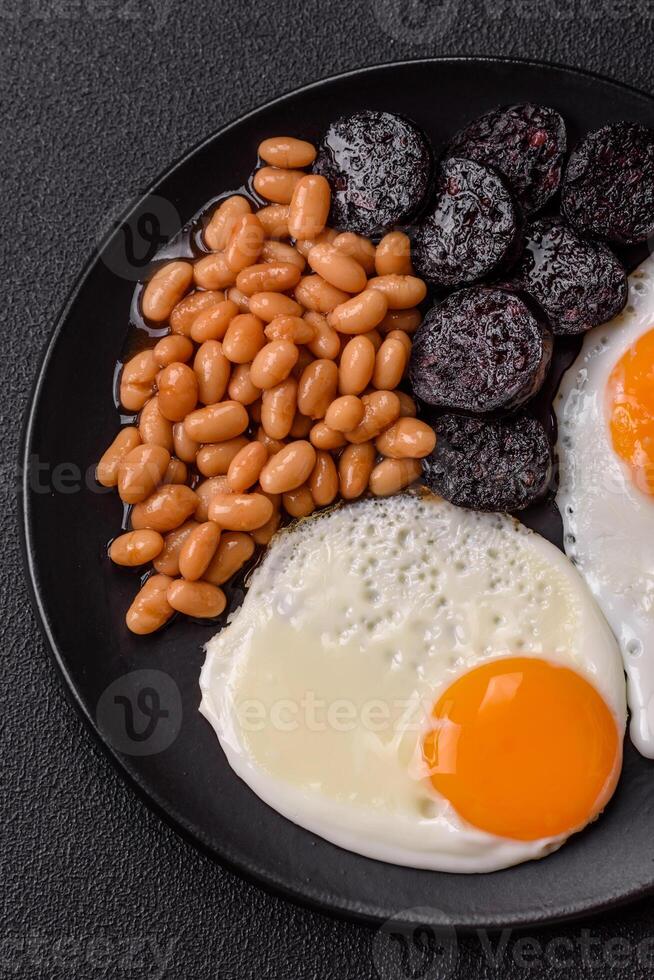 English breakfast with fried eggs, bacon, beans, tomatoes, spices and herbs photo