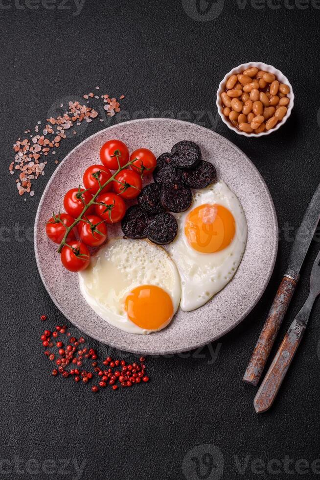 English breakfast with fried eggs, bacon, beans, tomatoes, spices and herbs photo