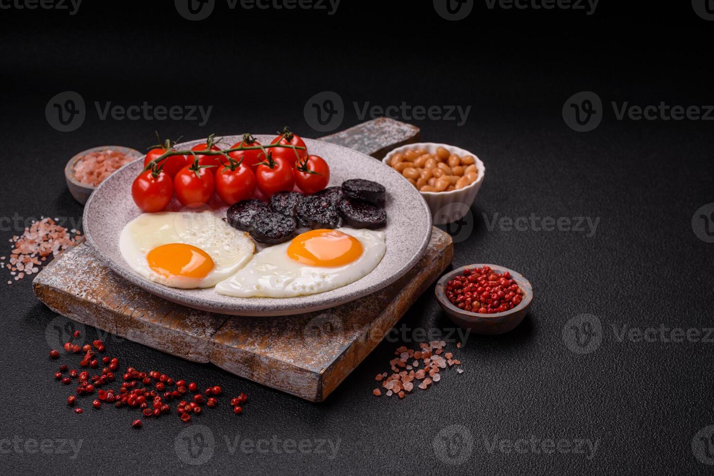 English breakfast with fried eggs, bacon, beans, tomatoes, spices and herbs photo