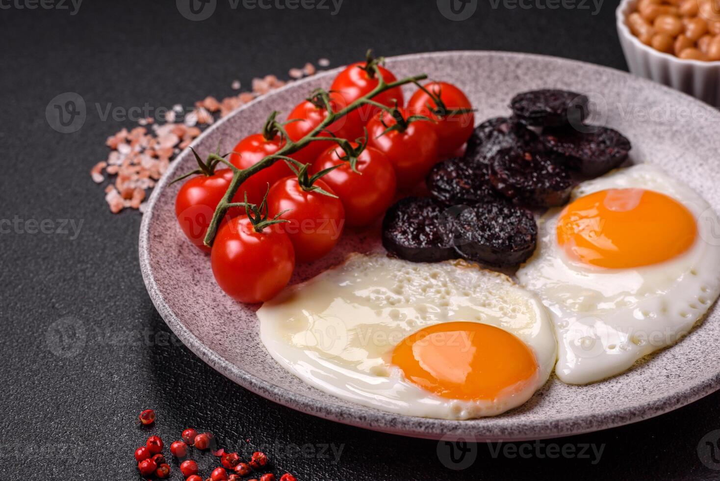 English breakfast with fried eggs, bacon, beans, tomatoes, spices and herbs photo