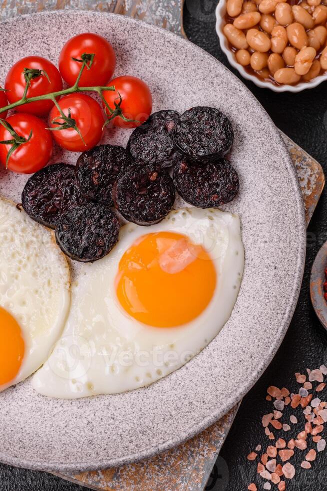 English breakfast with fried eggs, bacon, beans, tomatoes, spices and herbs photo