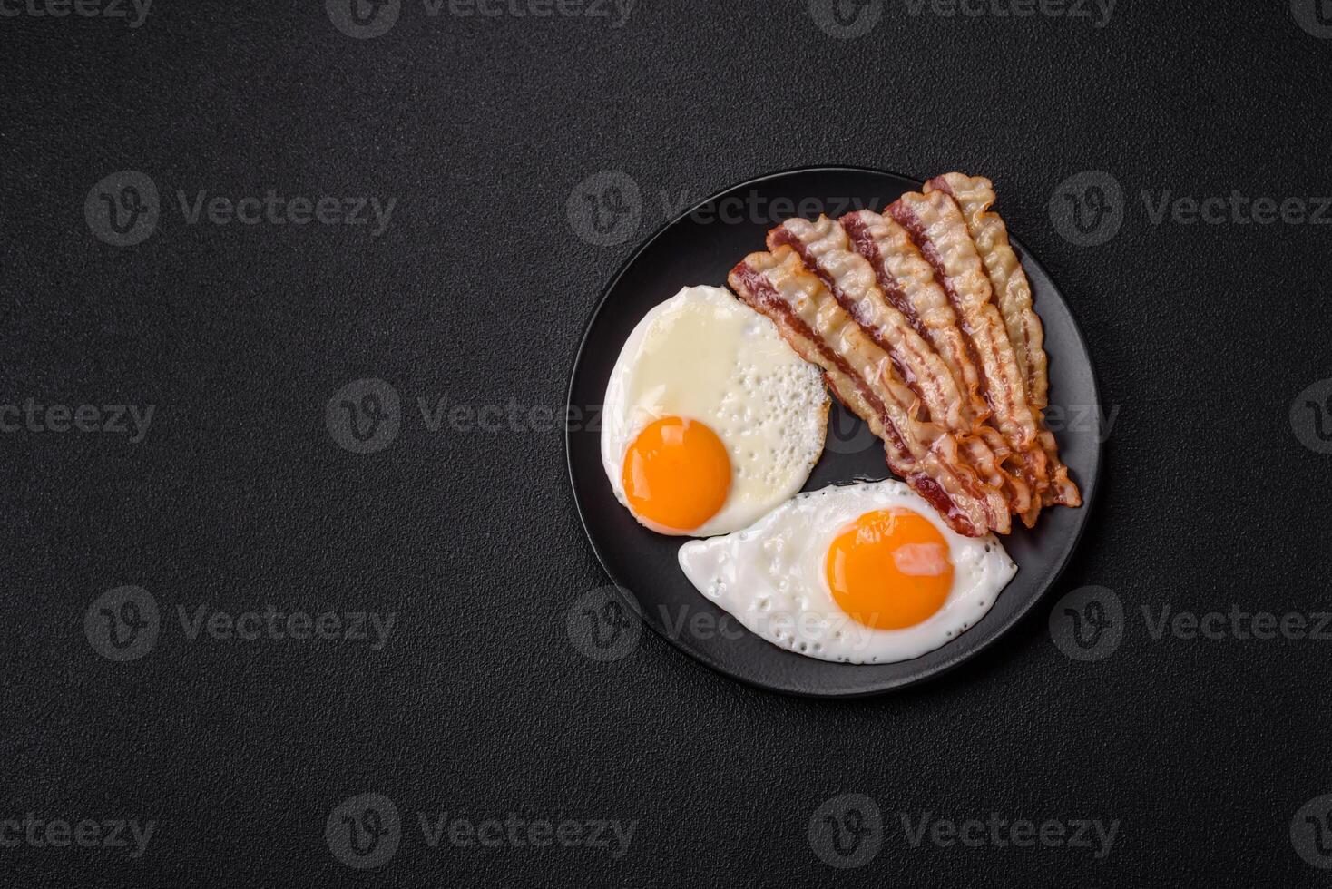 English breakfast with fried eggs, bacon, beans, tomatoes, spices and herbs photo