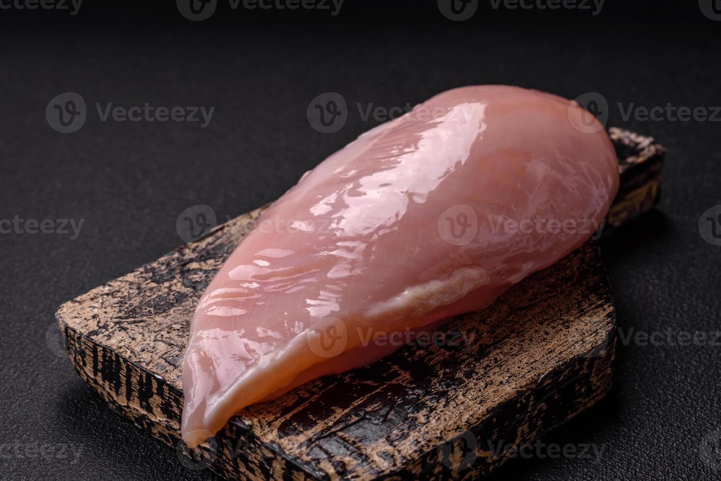 Fresh chicken fillet on a dark concrete table with spices and herbs photo