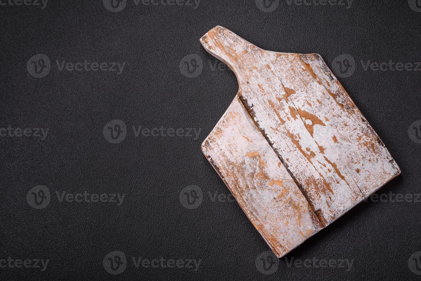 Empty wooden cutting board on dark textured concrete background photo