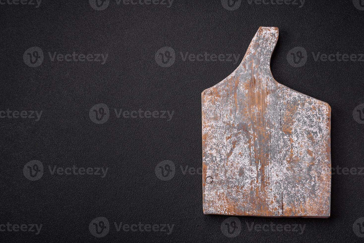 Empty wooden cutting board on dark textured concrete background photo
