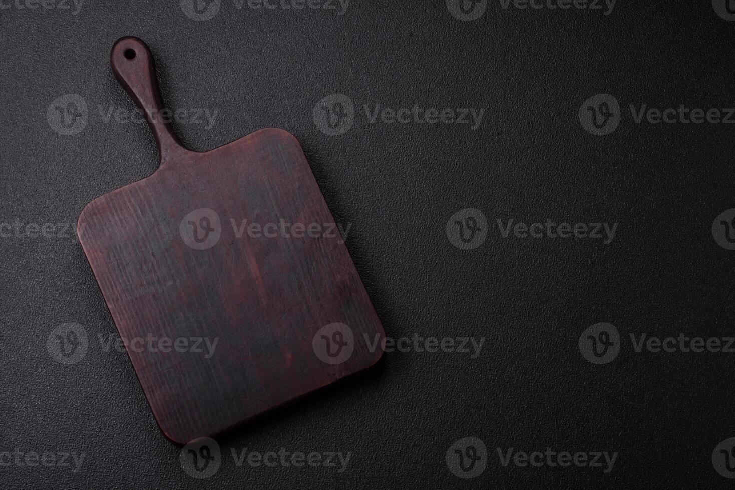 Empty wooden cutting board on dark textured concrete background photo