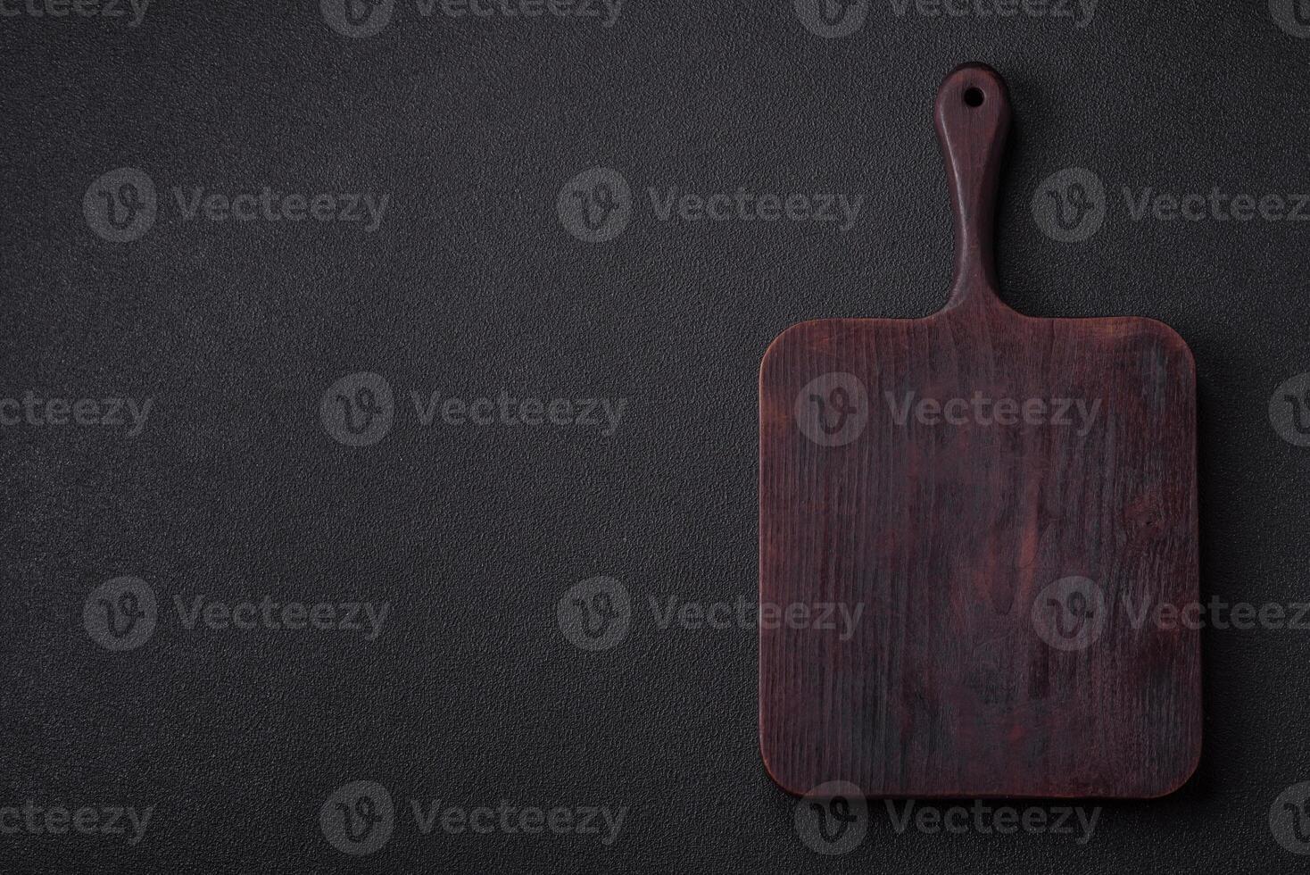Empty wooden cutting board on dark textured concrete background photo