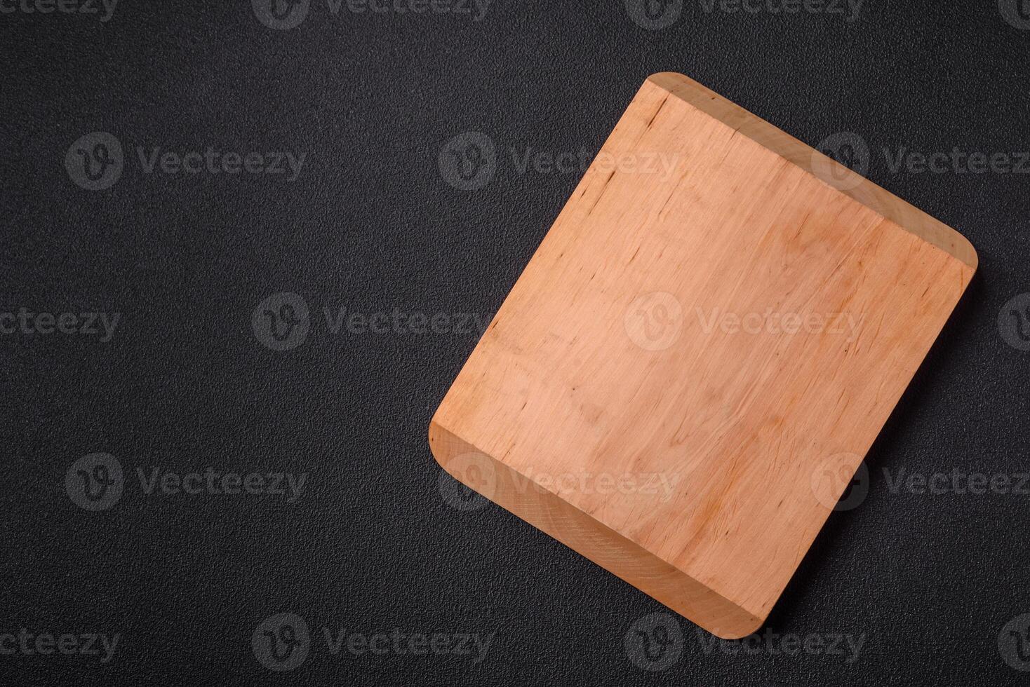 Empty wooden cutting board on dark textured concrete background photo