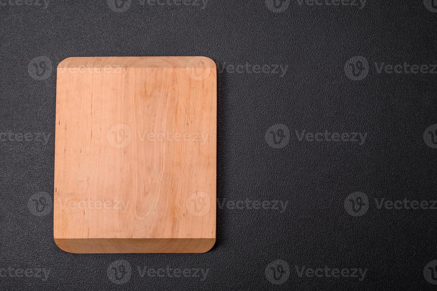 Empty wooden cutting board on dark textured concrete background photo