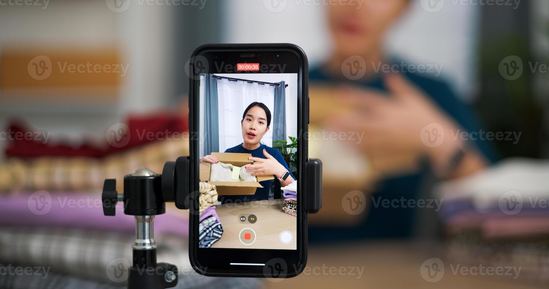 Selective focus, Young asian woman business owner selling clothes live streaming on mobile phone and packed clothes into box for a customer ,Online Shopping photo