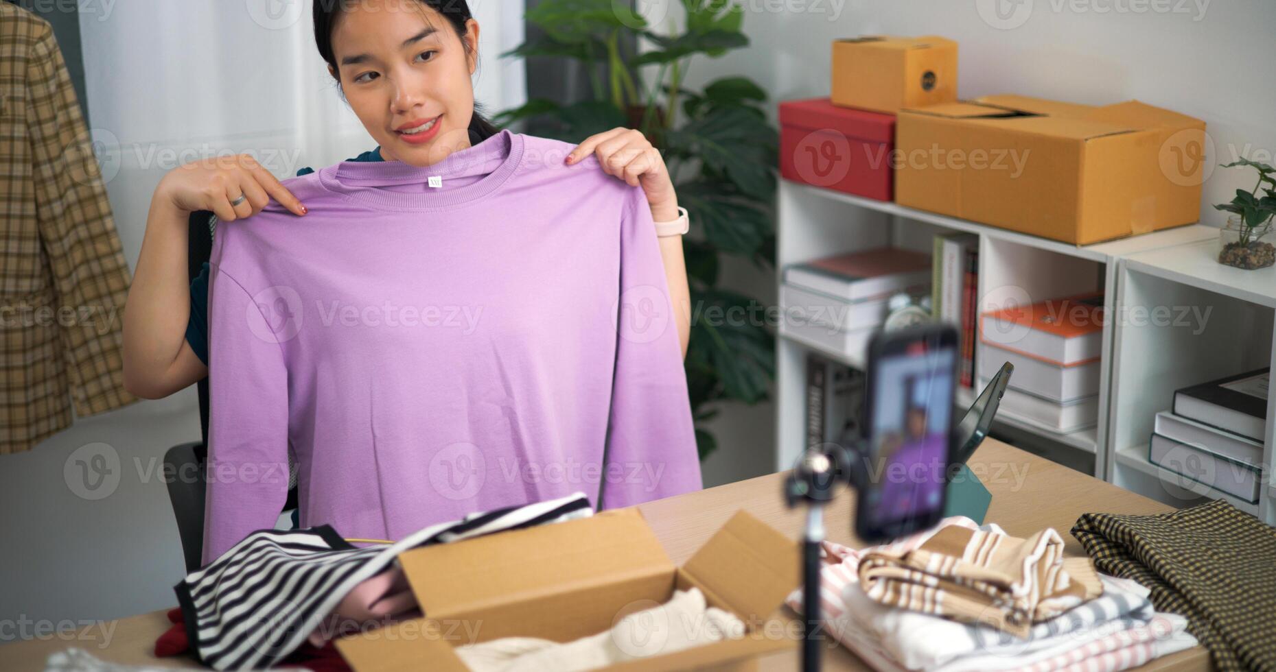 Portrait of Young asian woman business owner selling clothes live streaming on mobile phone show new collection fashion clothes to customer ,Online Shopping photo