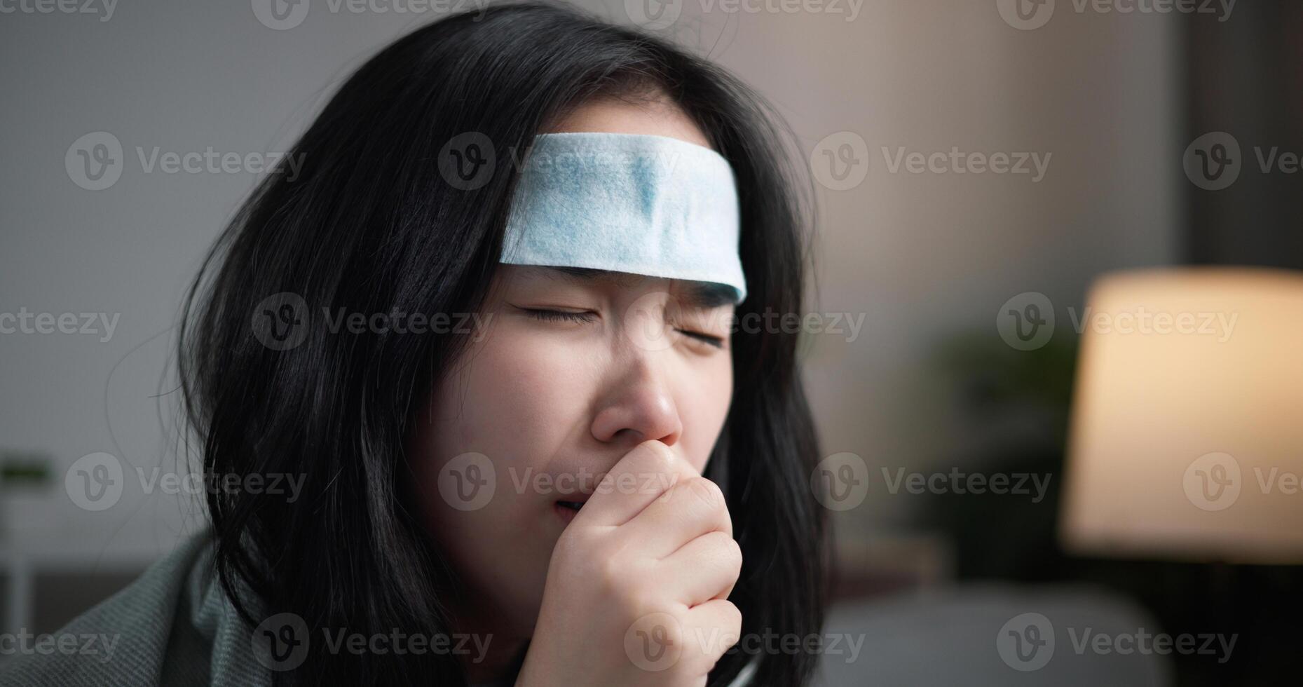 Portrait of Unwell young woman have a high fever feel chills and chronic cough ,wrapped in blanket sitting on sofa in the living room at home, healthcare woes photo