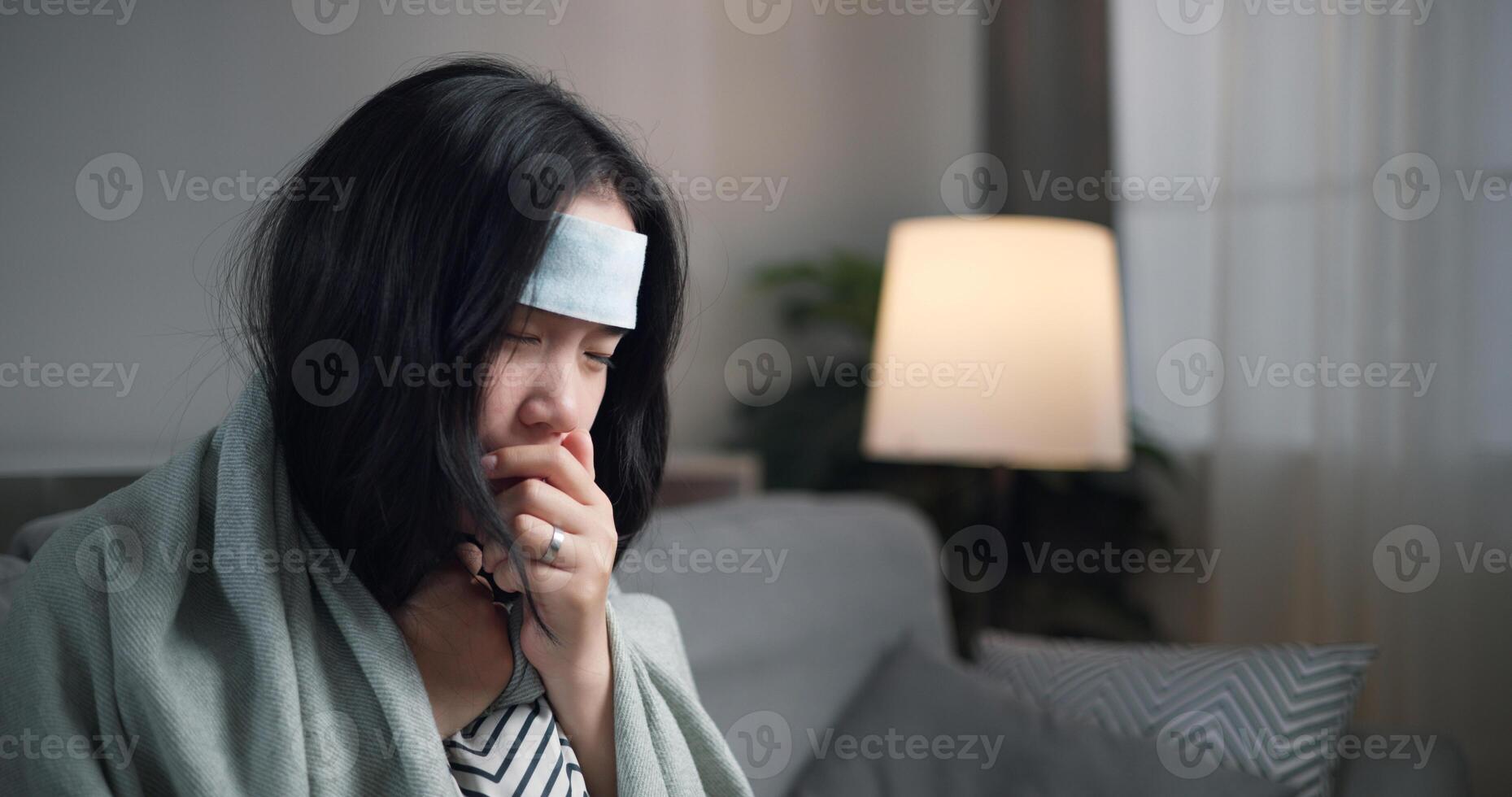 Portrait of Unwell young woman have a high fever feel chills and chronic cough ,wrapped in blanket sitting on sofa in the living room at home, healthcare woes photo