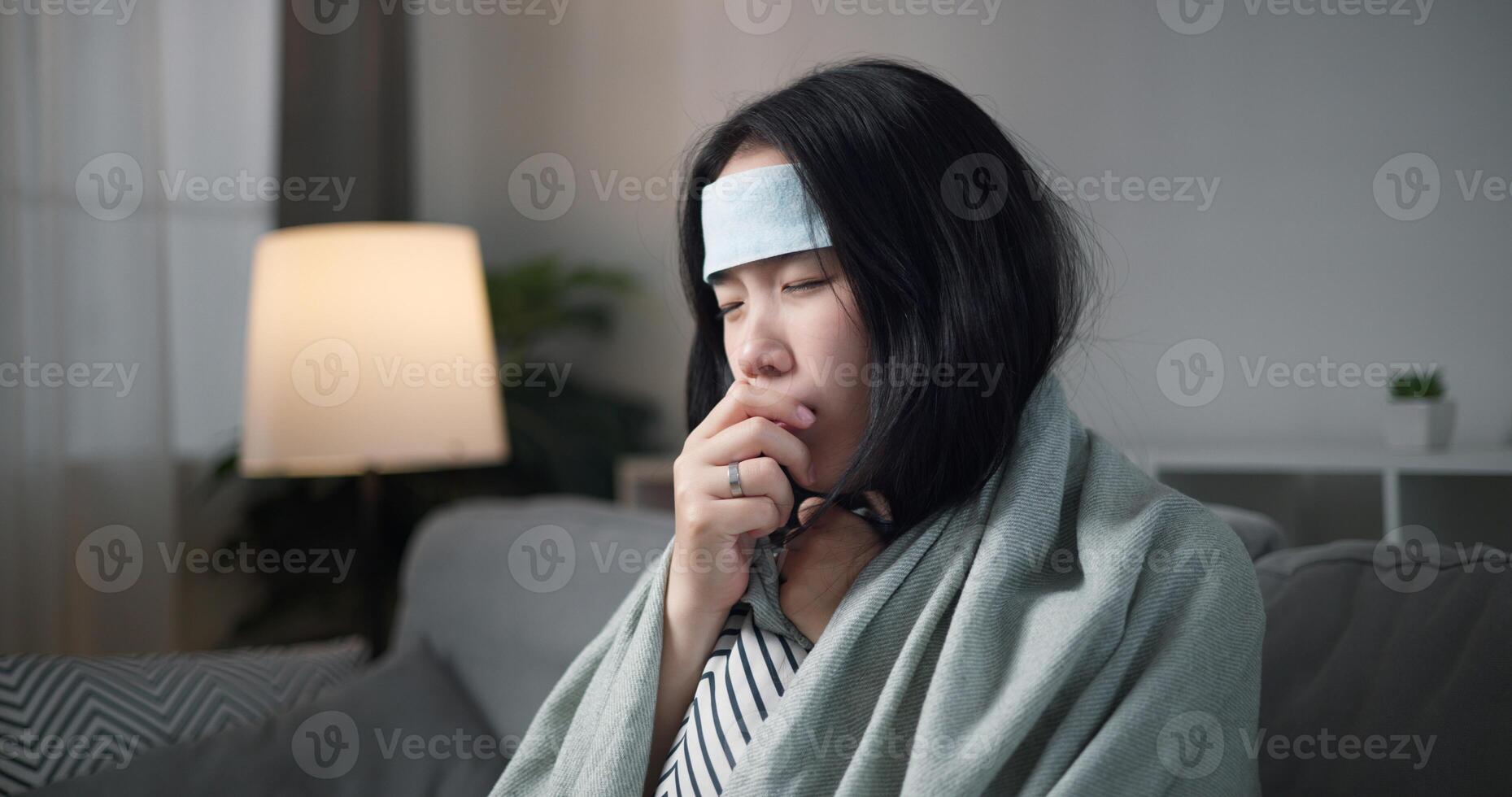 Portrait of Unwell young woman have a high fever feel chills and chronic cough ,wrapped in blanket sitting on sofa in the living room at home, healthcare woes photo