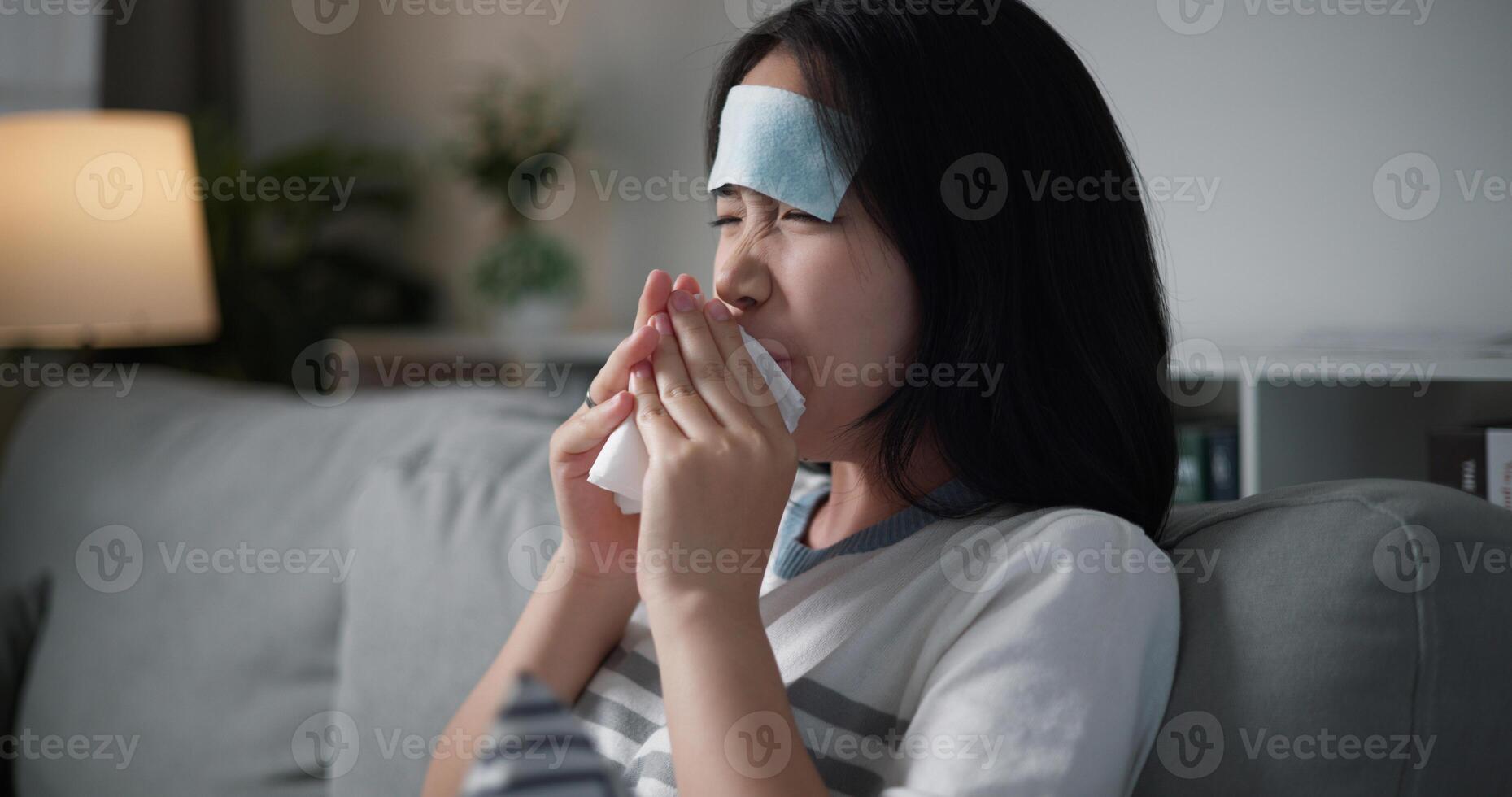 Portrait of Unwell young woman having a cold, sneezing and blowing your nose while sitting on sofa in the living room at home, healthcare woes photo