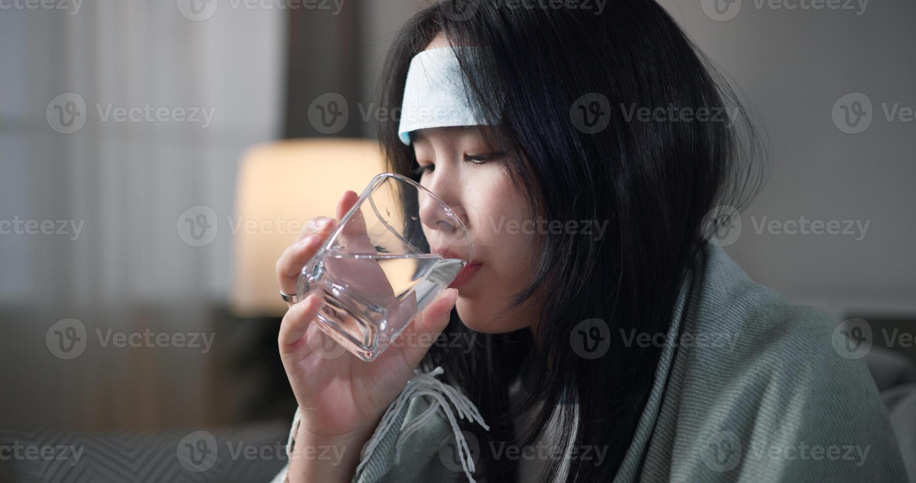 Portrait of Unwell young woman was drinking water, wrapped in blanket sitting on sofa in the living room at home, healthcare woes photo