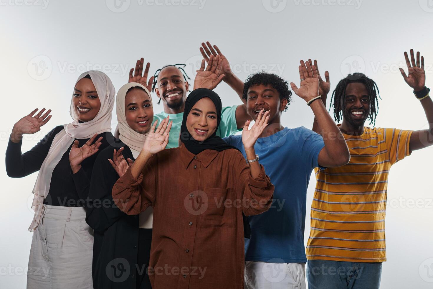 A jubilant and diverse group, including an African American man and hijab-wearing girls, exuberantly wave and celebrate, embodying the vibrancy of student life against a white backdrop, symbolizing photo