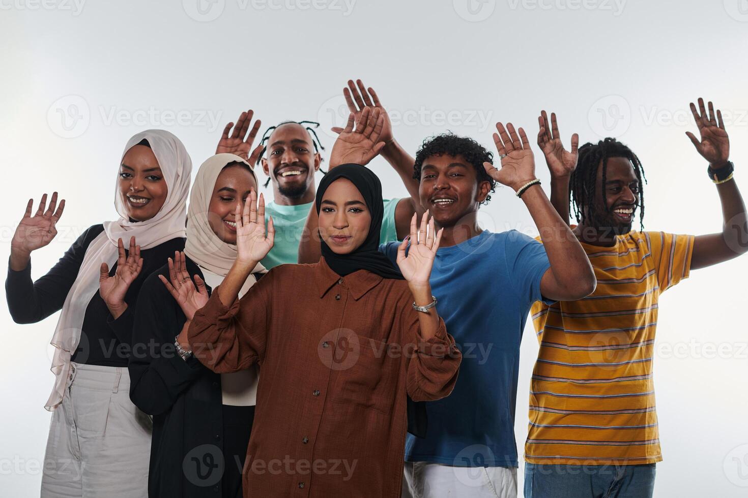 A jubilant and diverse group, including an African American man and hijab-wearing girls, exuberantly wave and celebrate, embodying the vibrancy of student life against a white backdrop, symbolizing photo