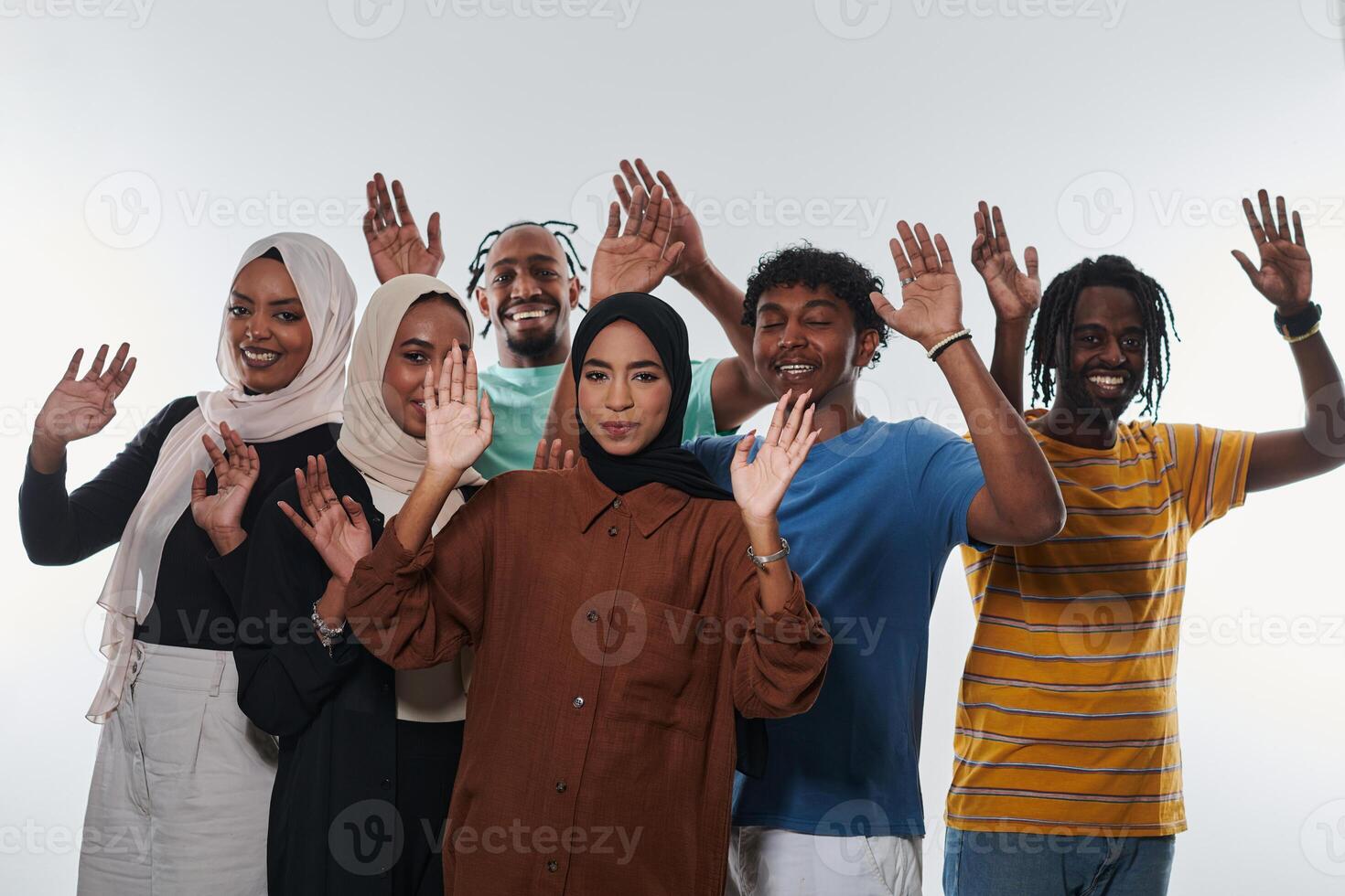 A jubilant and diverse group, including an African American man and hijab-wearing girls, exuberantly wave and celebrate, embodying the vibrancy of student life against a white backdrop, symbolizing photo