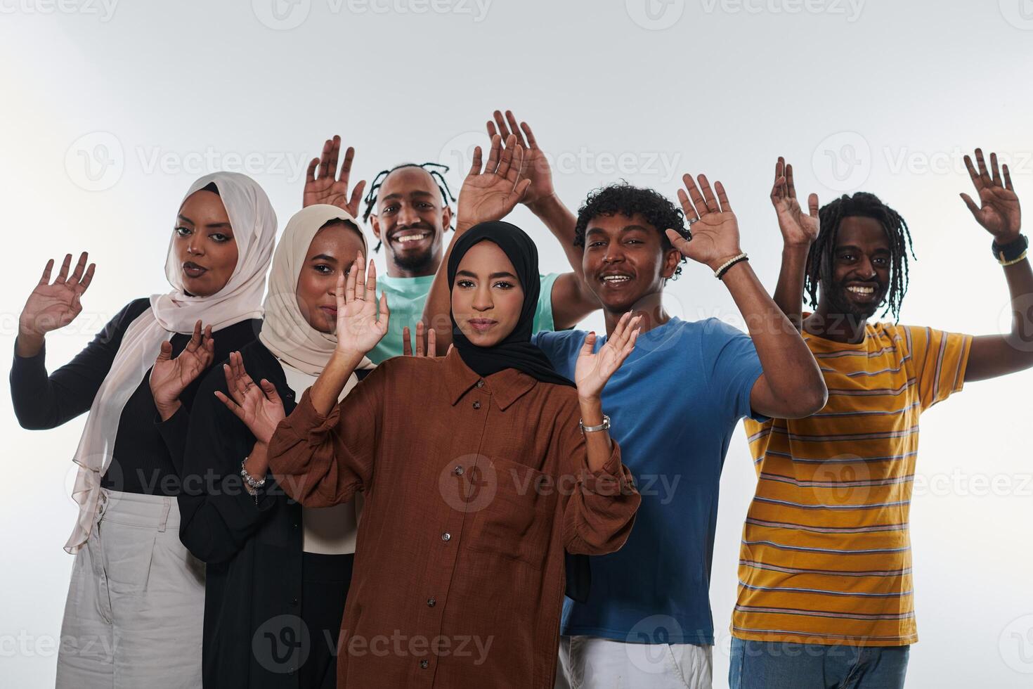A jubilant and diverse group, including an African American man and hijab-wearing girls, exuberantly wave and celebrate, embodying the vibrancy of student life against a white backdrop, symbolizing photo